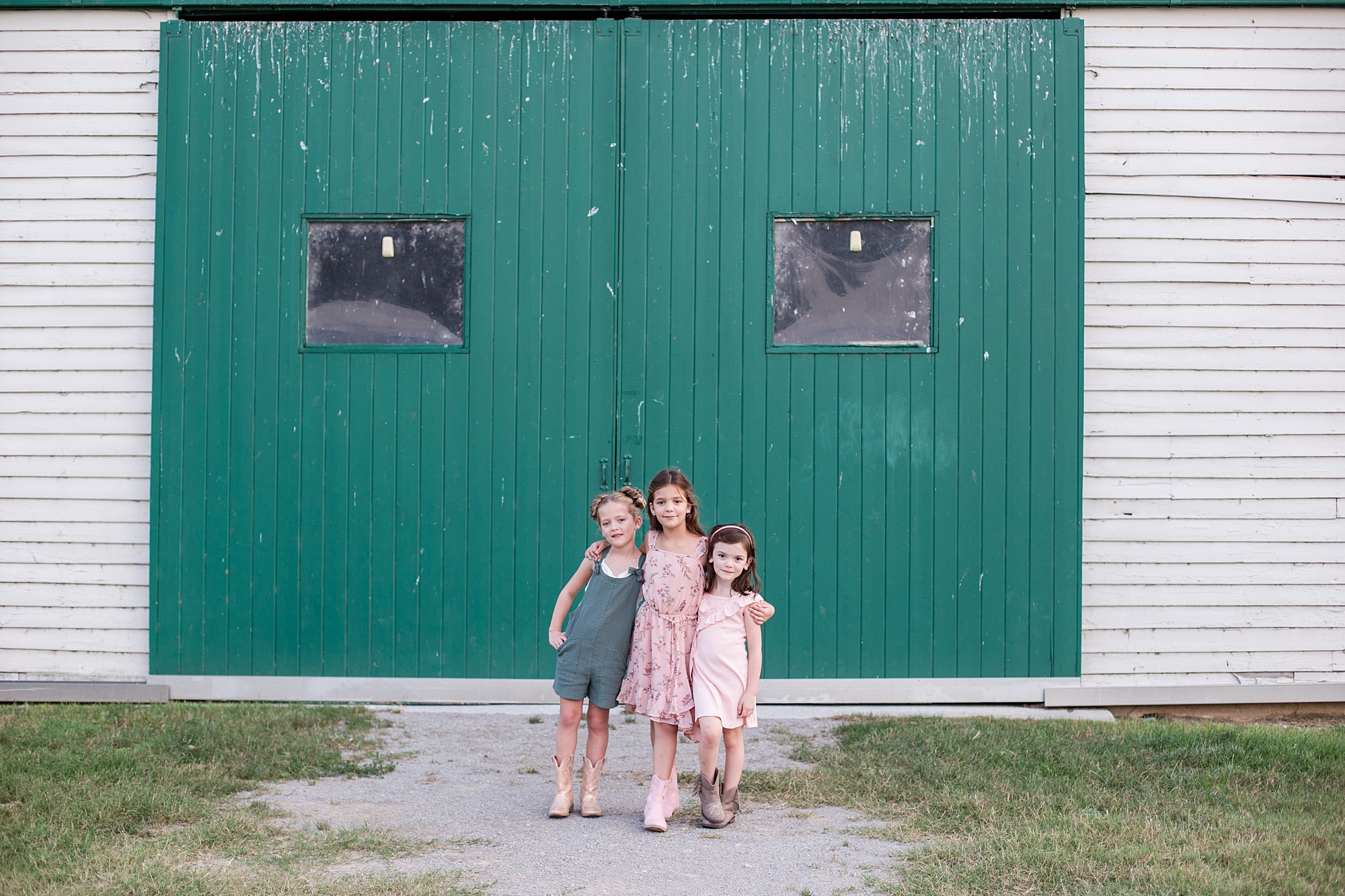 three girls hug in spring outfits by teal doors at Harlinsdale Farm