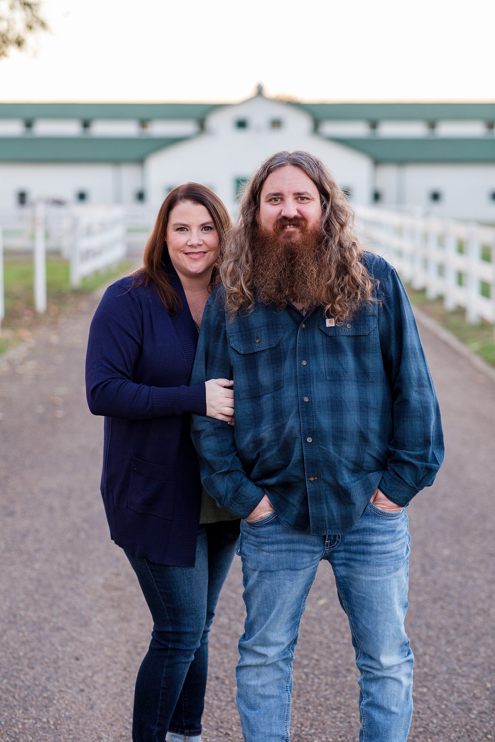 couple stands in front of white barn