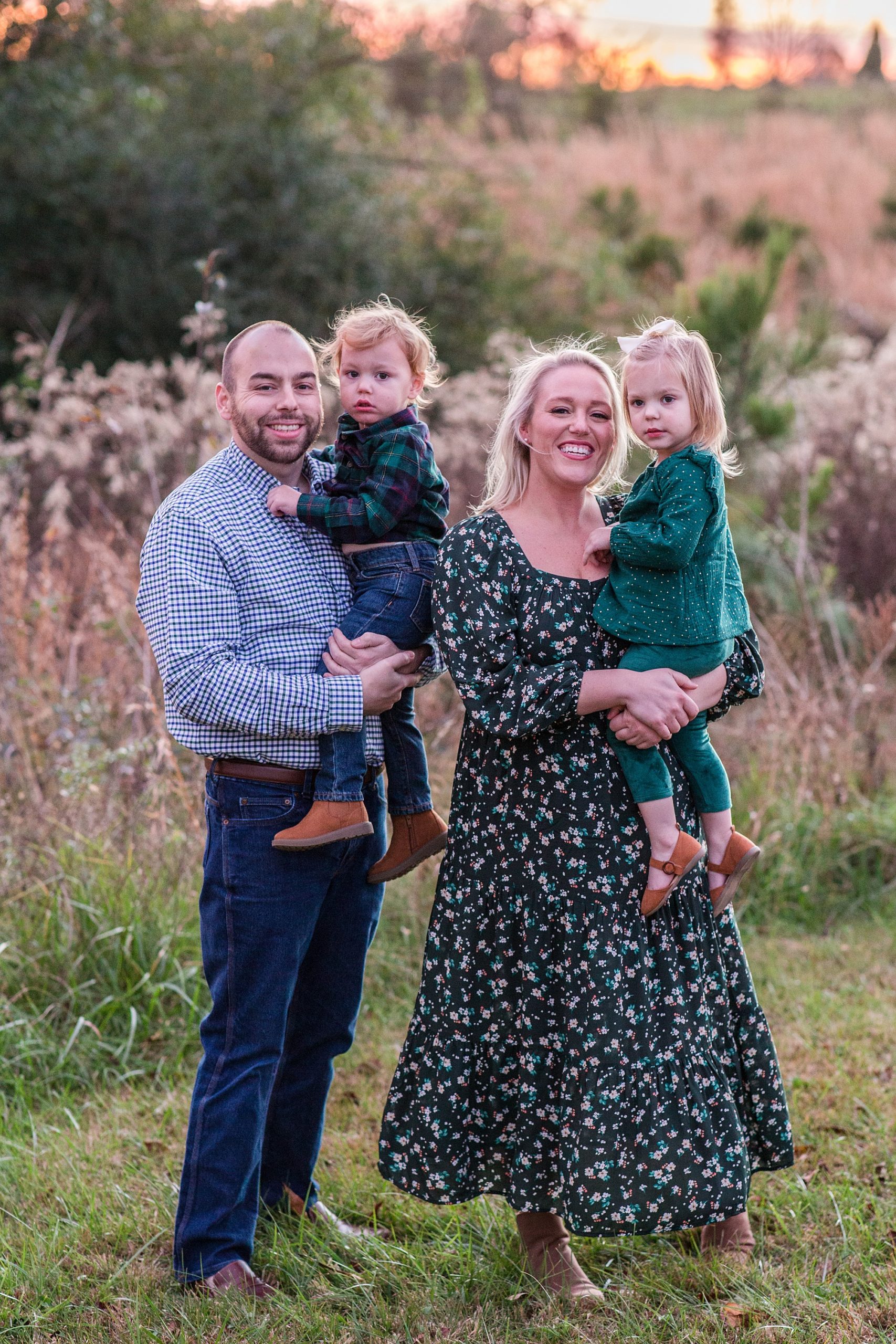 parents hug two toddlers at sunset during Pinewood Christmas Tree Farm family portraits 