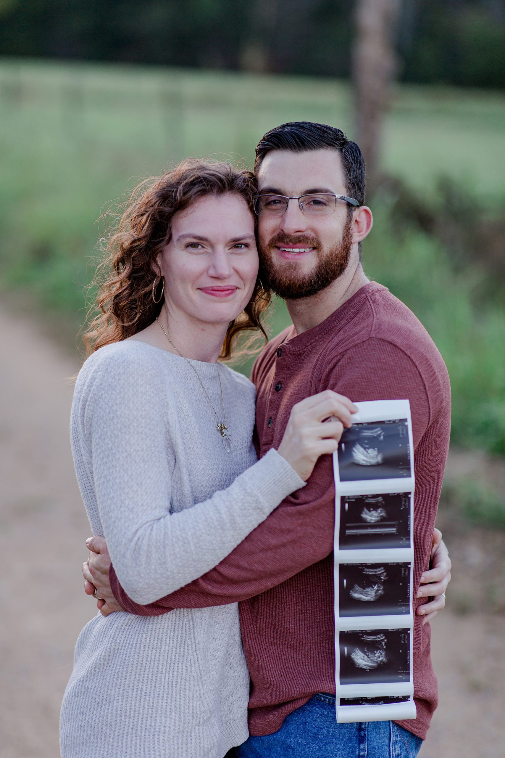 husband and wife hug in field during TN pregnancy announcement 