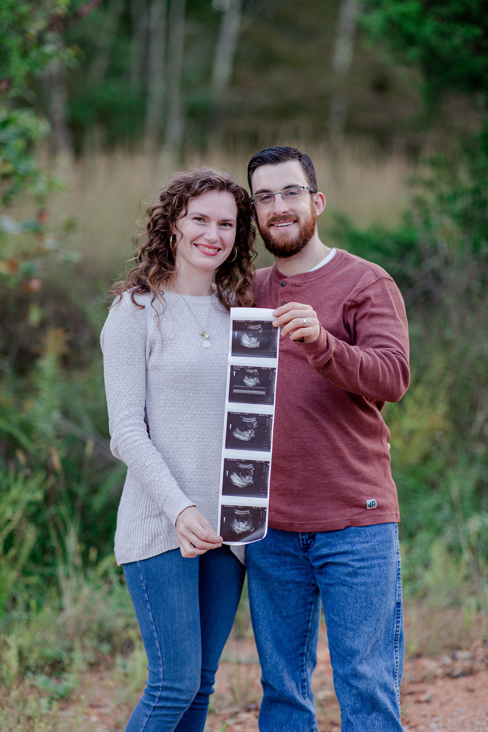 man and wife hold sonogram during pregnancy announcement session