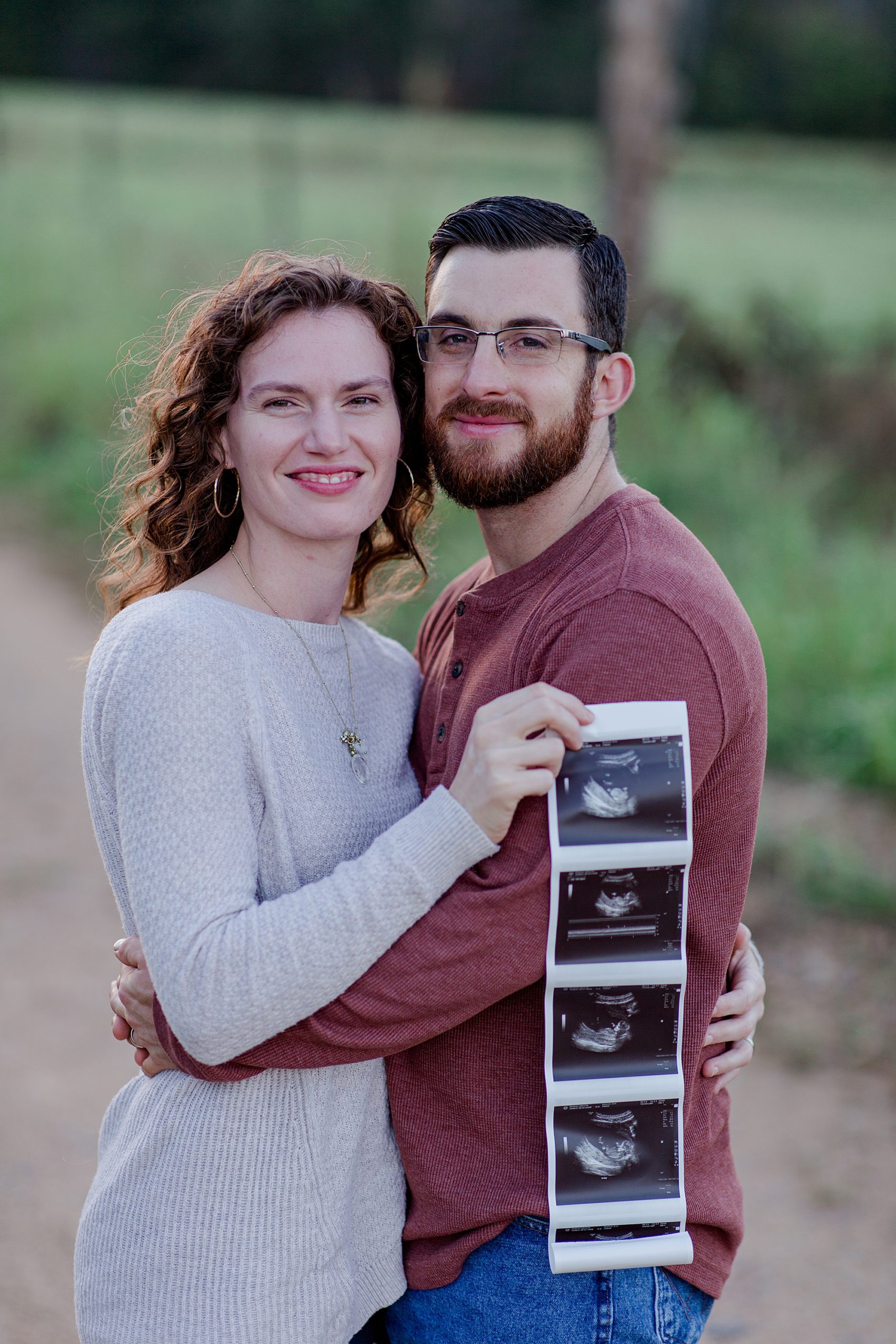couple hugs holding sonogram during Pregnancy Announcement in Hickman County, TN