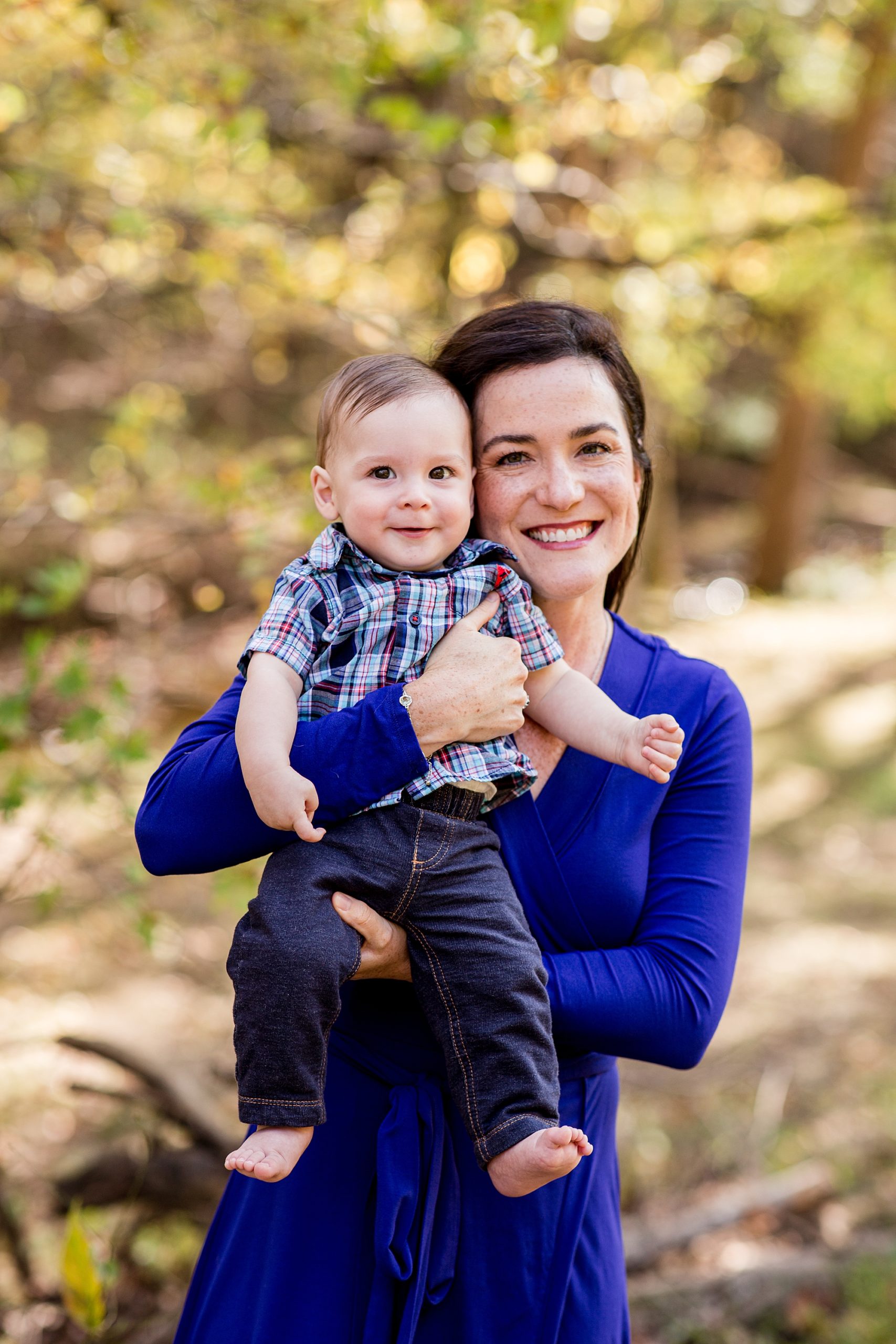 mom in blue dress smiles with son during family photos