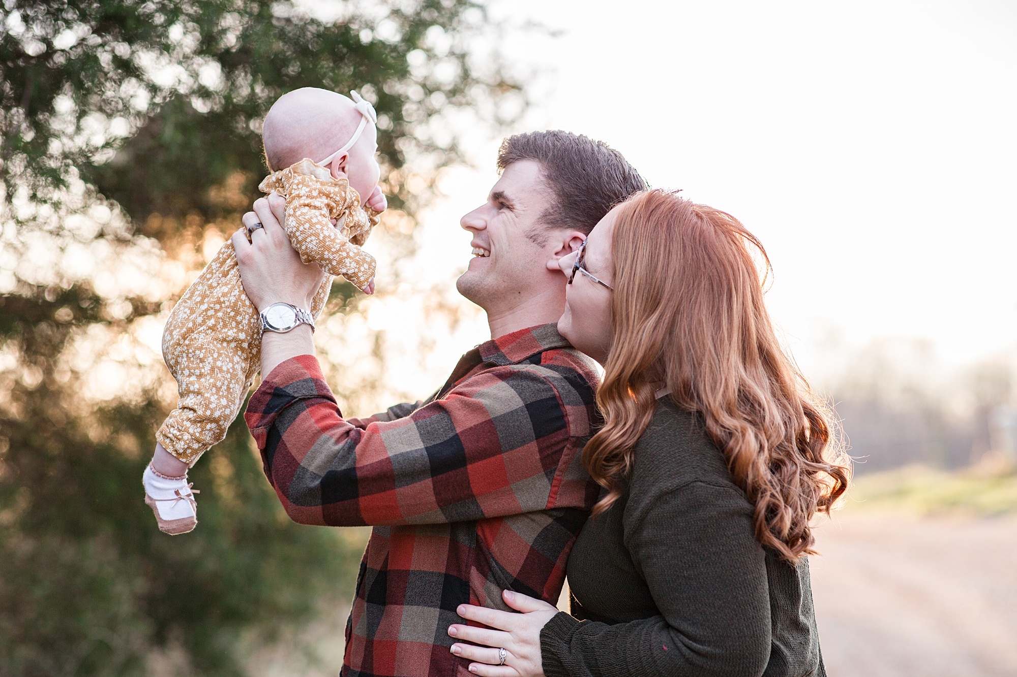 new parents smile at baby girl during family photos