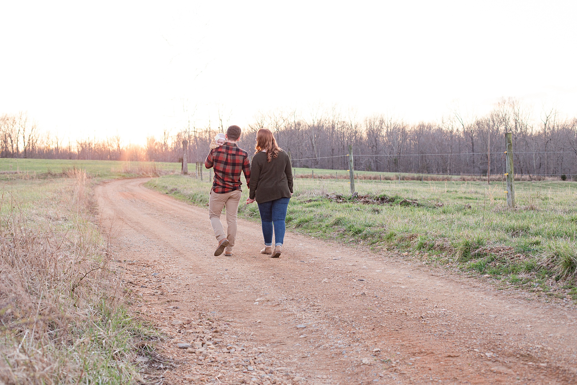 parents hold hands walking down dirt path