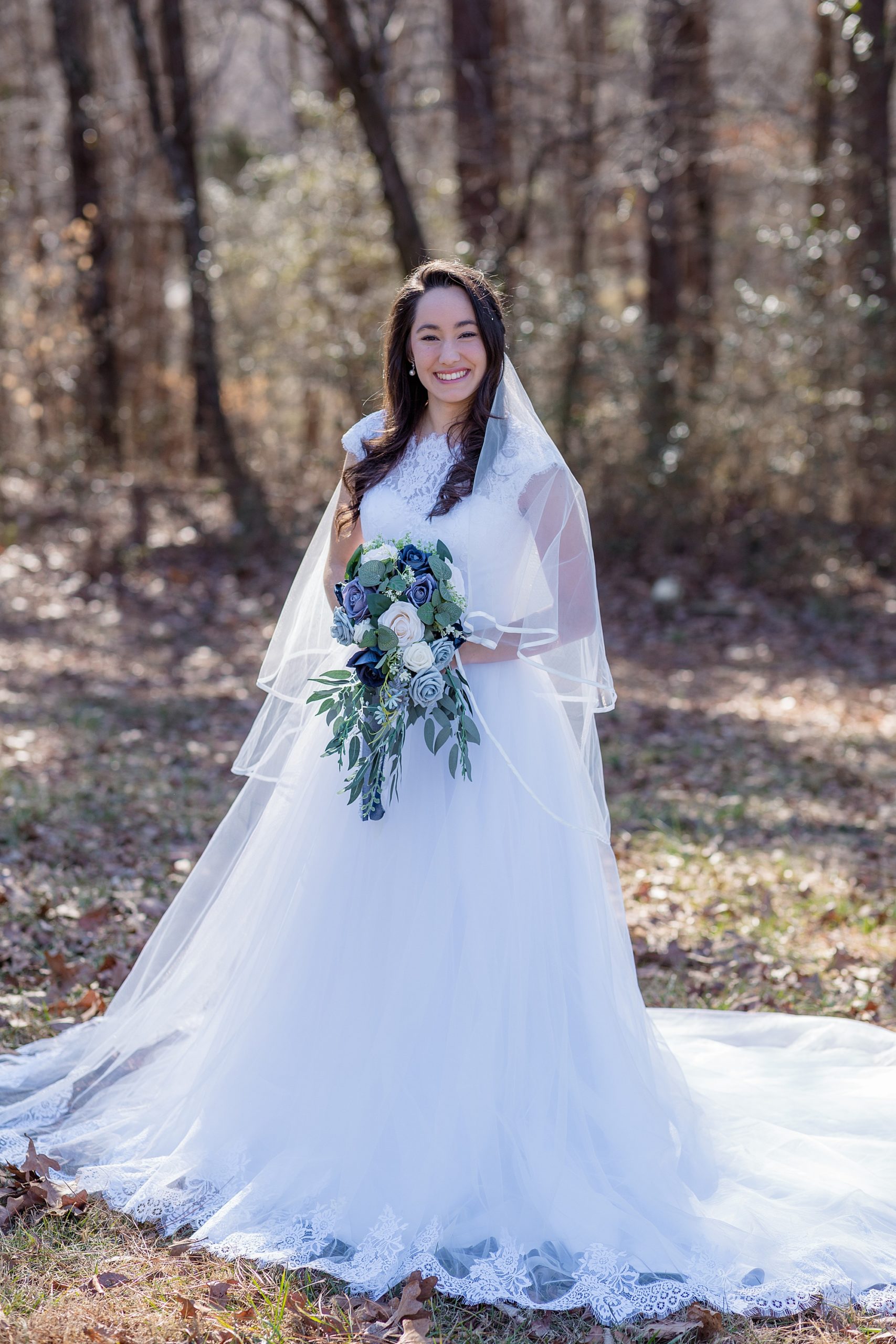  bride stands holding cascading bouquet