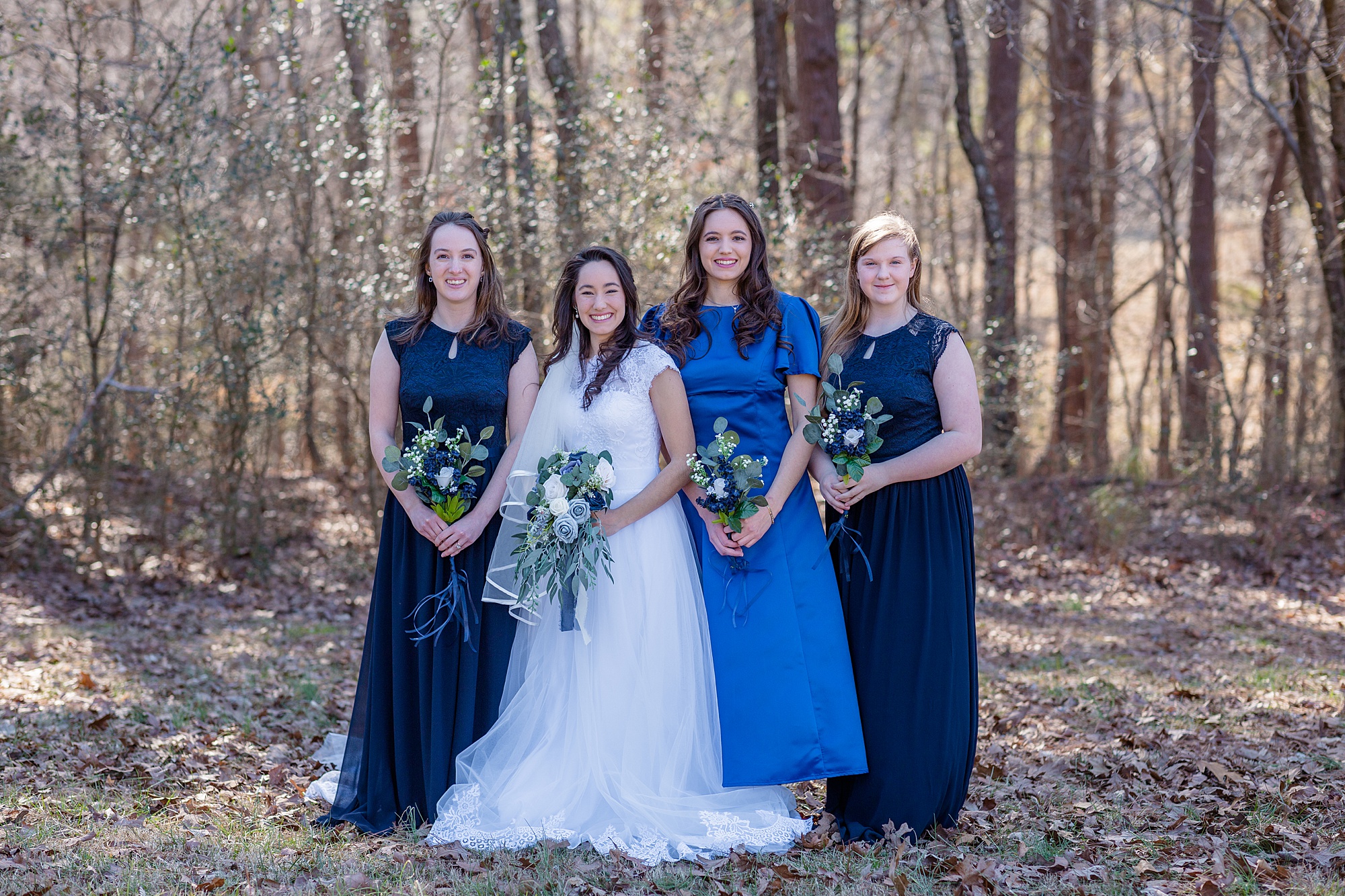 bride poses with bridesmaids in navy and blue gowns