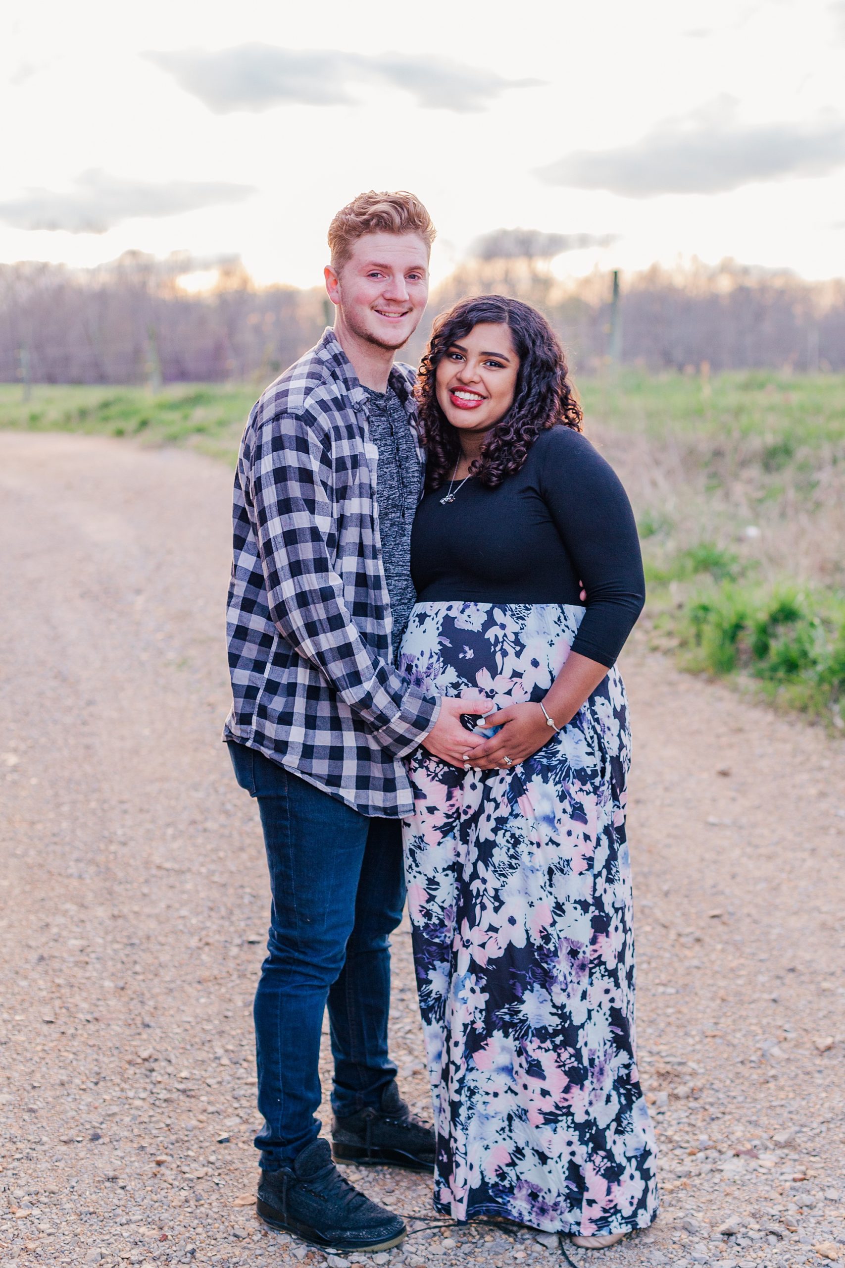 man holds wife's stomach during  sunset maternity session
