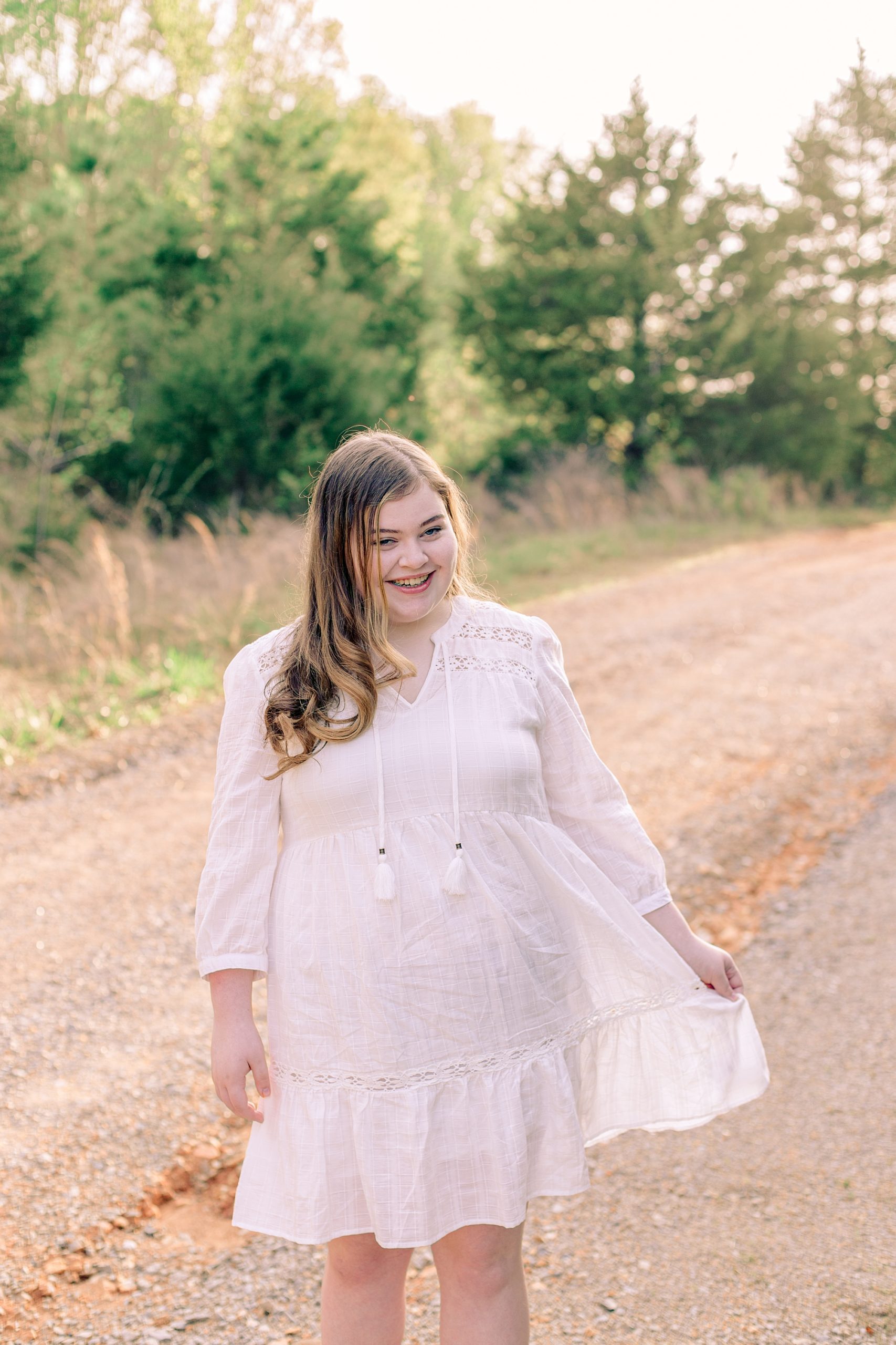 girl twirls her white dress during Tennessee senior portraits on pathway