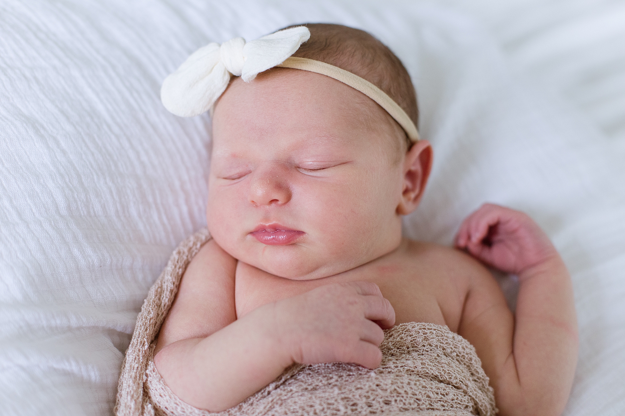baby lays in white bow during newborn photos at home