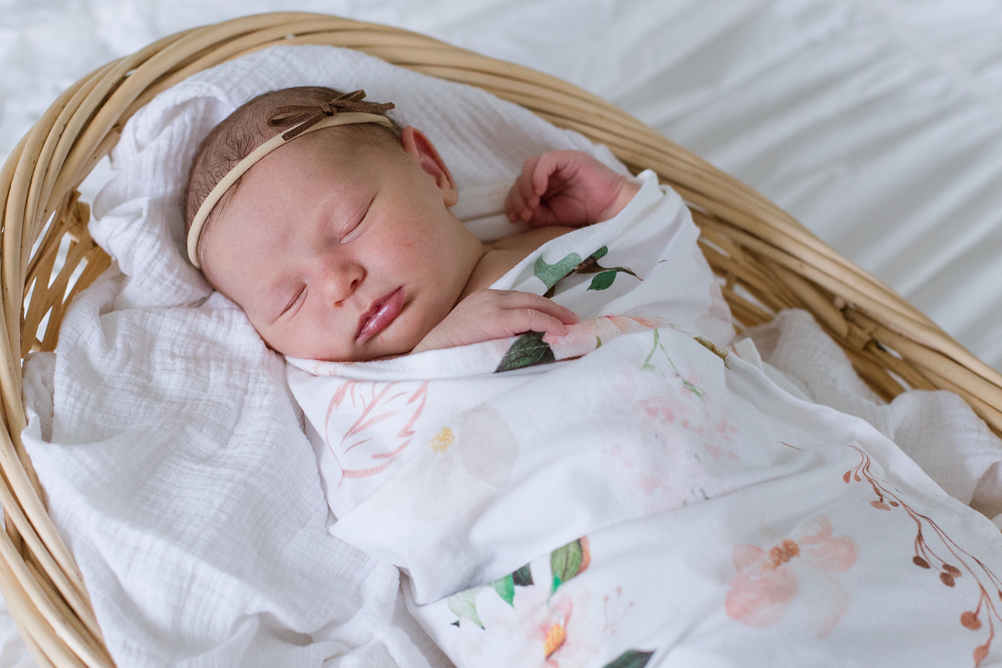 baby girl lays in wicker basket during lifestyle newborn session